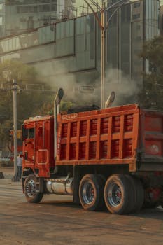 A red truck on a busy street in Ciudad de México, showcasing urban life and city architecture.